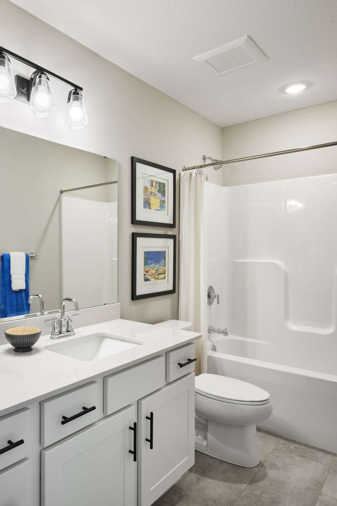 Modern bathroom with white fixtures and framed art.