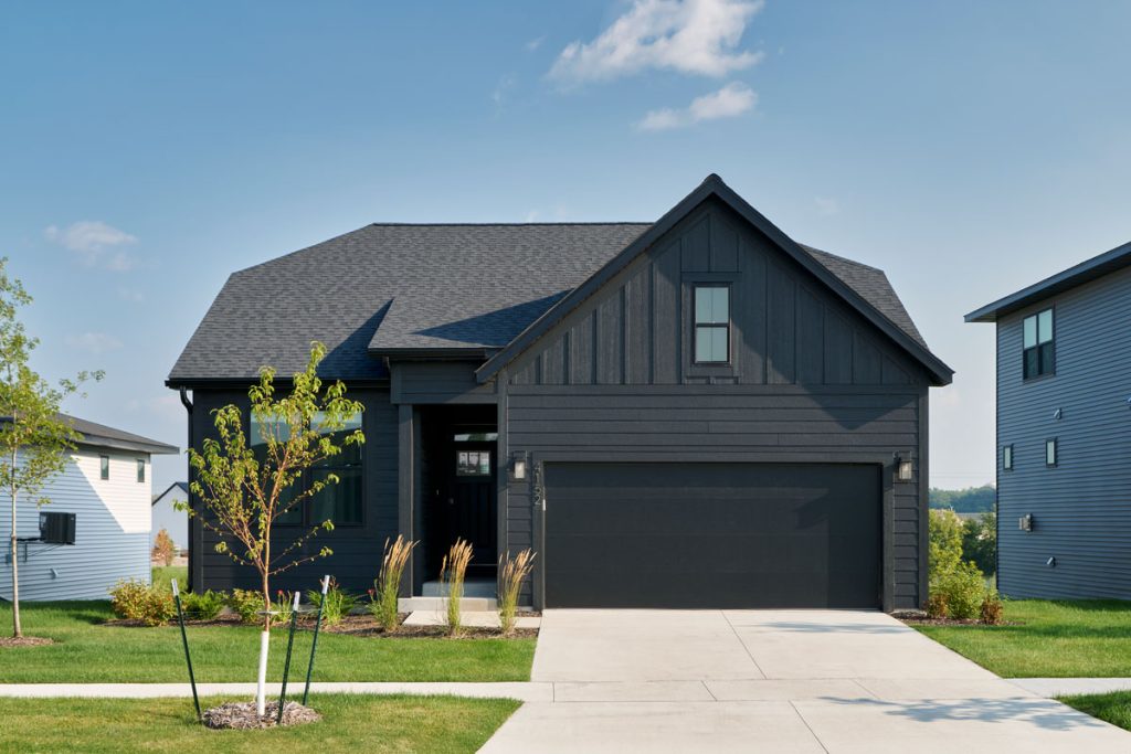 Modern black house with lawn and driveway.