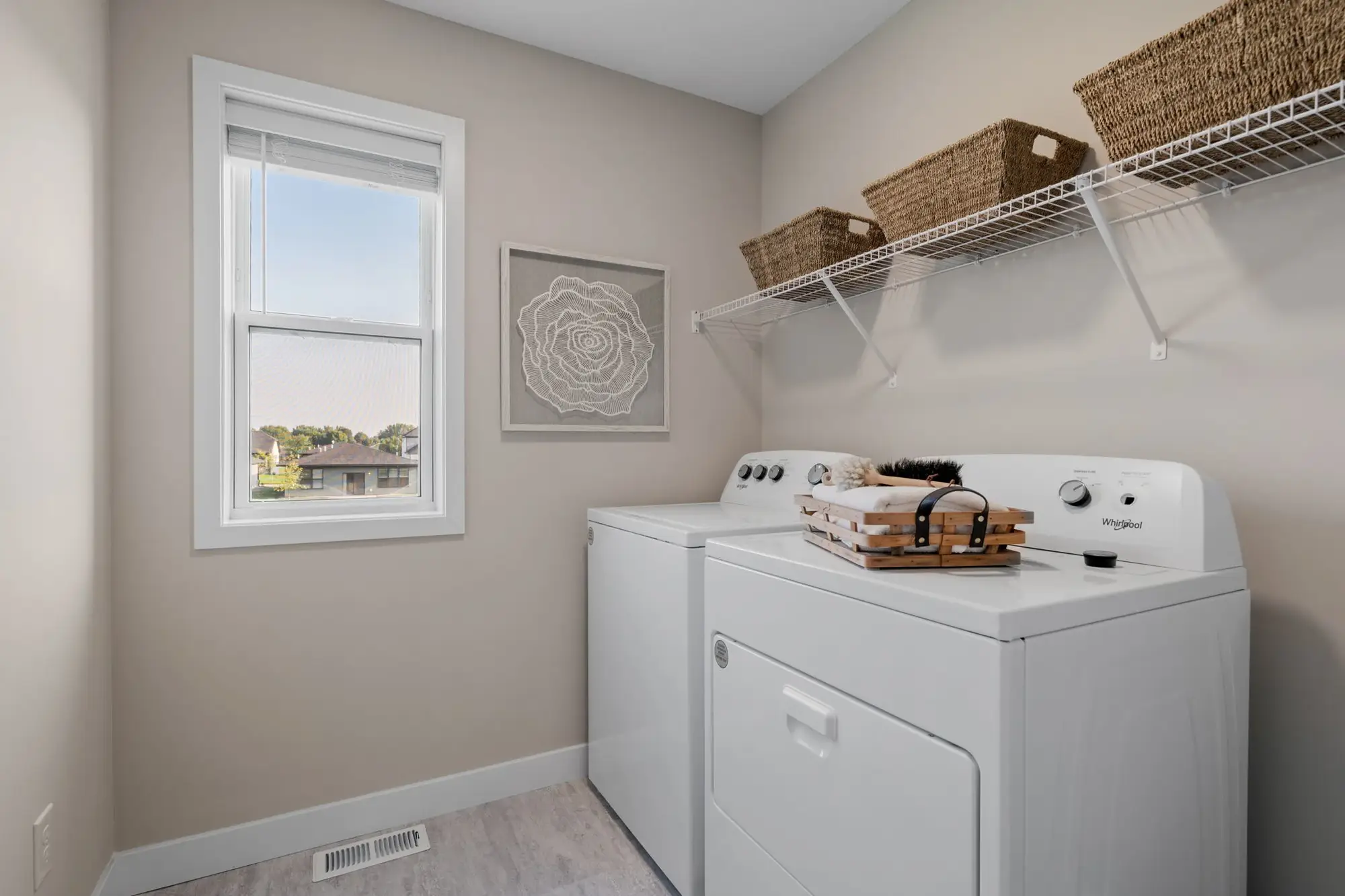 Modern laundry room with washer, dryer, window, and baskets.